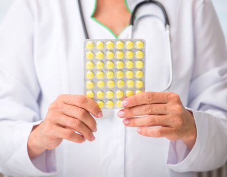 doctor holding a pack of yellow pills in hands