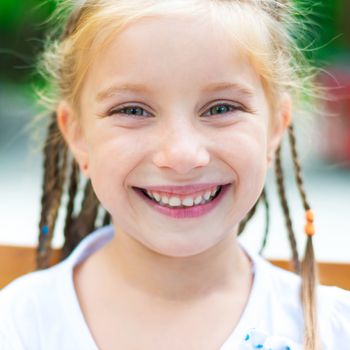 cute little girl smiling in a park close-up