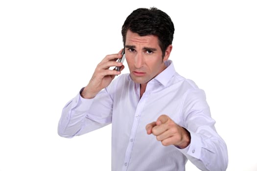 Confident businessman pointing whilst making telephone call