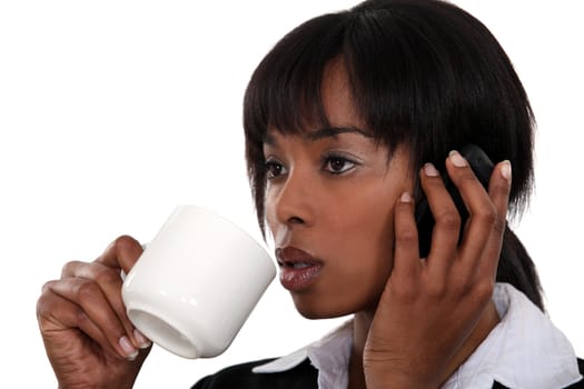 Businesswoman drinking coffee whilst telephoning