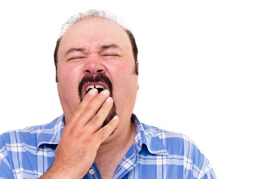 Tired man yawning with his hand to his mouth as he tries to fight off his exhaustion, isolated on white