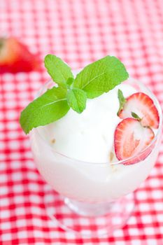 ice cream with mint in a glass bowl and strawberry on plaid fabric