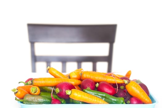 heap of vegetables on a table and a chair isolated on white
