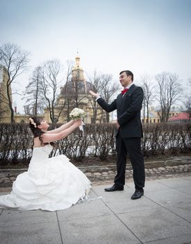 bride on her knees gives a bouquet to the groom on the street