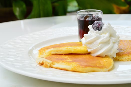 pancake with wipcream and blueberry syrup on white plate