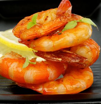 Delicious Grilled Shrimps with Lemon and Thyme closeup on Black plate