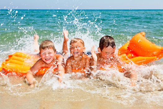 Three kids splashing water on a beach