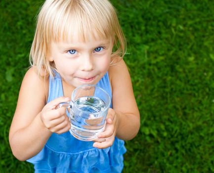 Little girl holding glass of water outdoors
