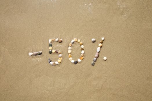 fifty percent discount word writing with small stones on sand beach ground
