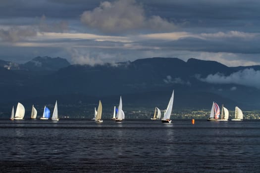 Colorful sailboat sailing on a calm evening with dramatic sunset, Geneva lake, Switzerland