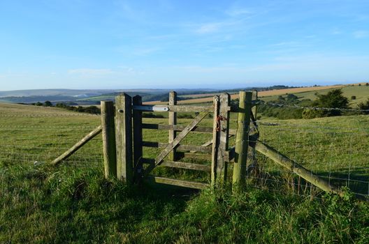 Wood gate leading to open countryside with a clear blue sky above.Shot taken in the Summer of 2013 on Ditchling Beacon,Sussex,England.