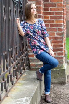 Full-length portrait of a pensive girl near old fence