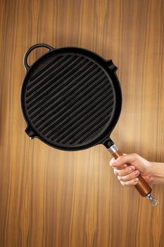 Man holding a cast iron frying pan of grill pan type. 