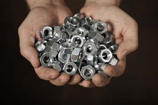 Man holding metallic nuts in his hands.
