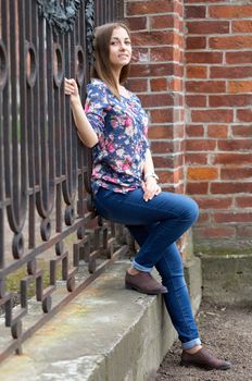 Full-length portrait of a pensive girl near old fence,