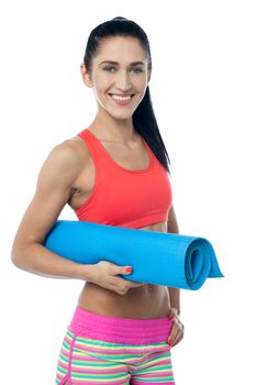 Cheerful female fitness instructor holding blue mat