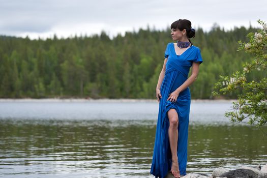 girl in a luxurious evening dress on the lake shows a slim leg