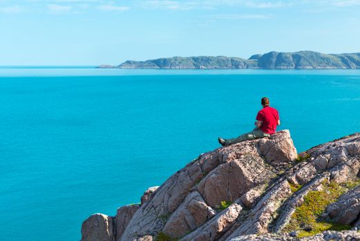 man sitting on a rock overlooking the sea