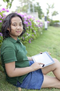 girl sittingon green grass with computer tablet in hand use for people and technology theme