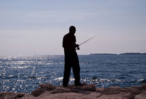 man fishing in the sea - silhouette of a fisherman