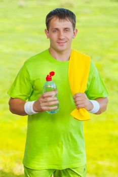 a sportsman holding bottle of water and looking at camera