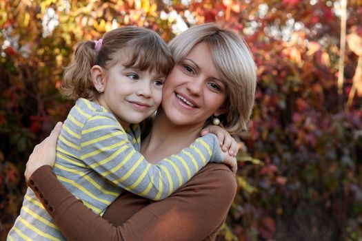 happy mother and daughter portrait in autumn park