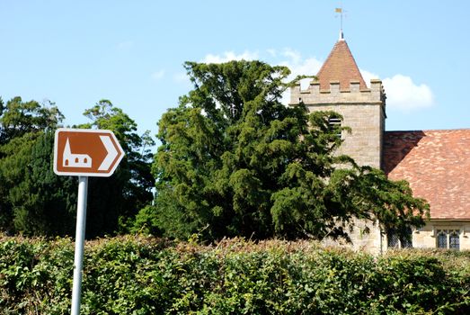 Brown tourist sign pointing towards the historic church of St Thomas a Becket in Kent