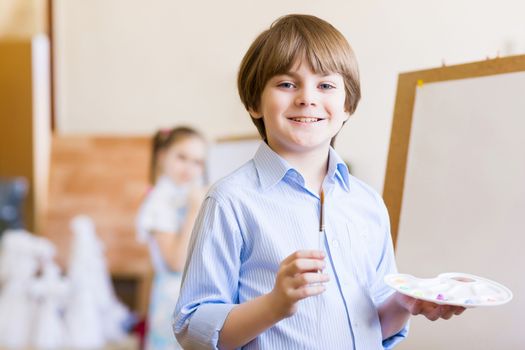 Image of little cute boy painting pictures at kindergarten