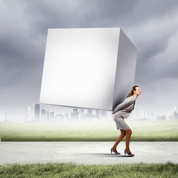 Image of businesswoman carrying big white cube on her back. Place for text