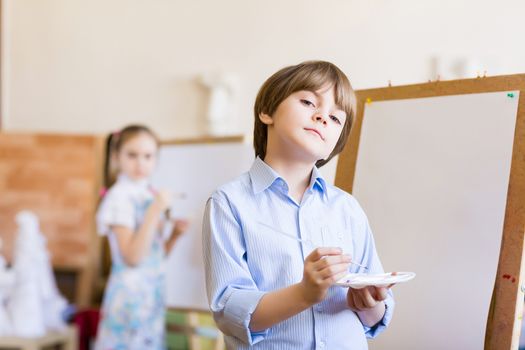 Image of little cute boy painting pictures at kindergarten