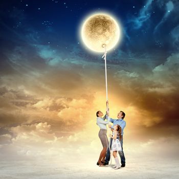 Image of young happy family pulling moon