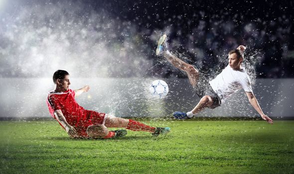 two football players in jump to strike the ball at the stadium