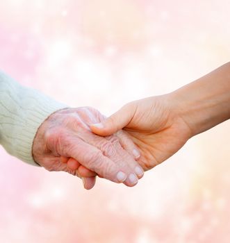 Senior Lady Holding Hands with Young Woman on Pink Lights Background 