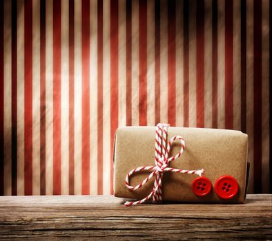 Handmade gift box with red twine cord over striped background