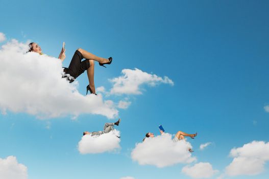 Image of businesspeople lying on clouds with tablet pc