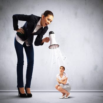 Angry businesswoman with megaphone shouting at colleague