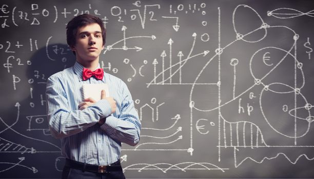 Image of thoughtful male student holding notebook in classroom