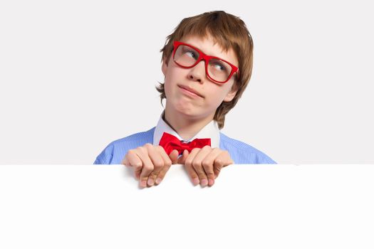 Image of young boy smiling thoughtfully holding white square. Place for advertisement