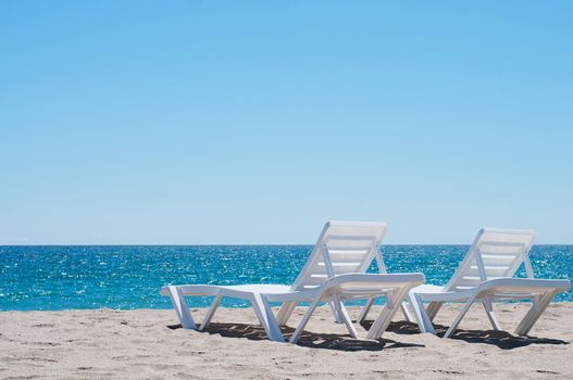Two sunloungers on the beach, blue sky