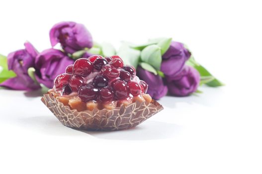 Berry cake and fresh violet tulips on the white