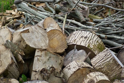 Pile of heavy wood logs for winter heating stacked outdoors        