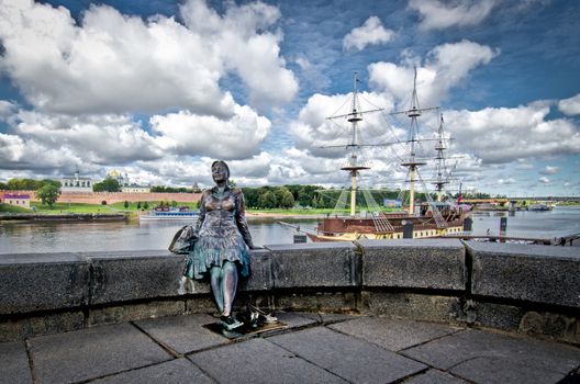 Statue of a lady taking a rest on the river bank wall in Novgorod, Russia