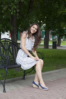 Beautiful young woman sits on a bench