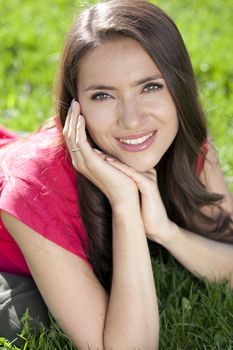 Portrait of young woman lying on a green lawn