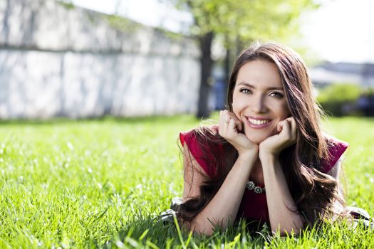 Portrait of young woman lying on a green lawn