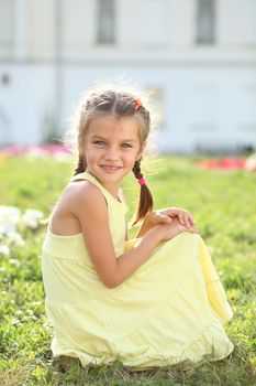 Portrait of a happy little girl sitting on the grass
