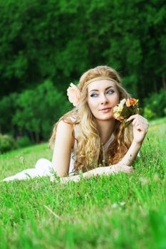 Romantic woman with roses lying among green grass