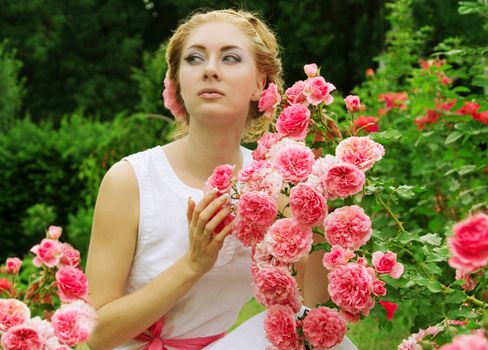 Sensual woman in pink rose garden walking