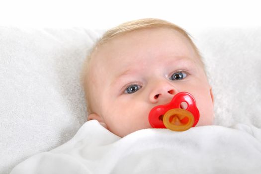 Baby Boy with pacifier lying on the White blanket