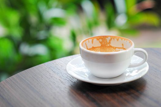 Empty coffee cup on the wood table near the garden